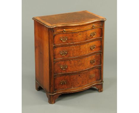 A walnut veneered and crossbanded serpentine fronted chest of four drawers with slide, with brass drop handles and cockbeadin