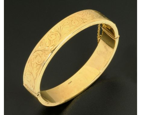 A 9 ct gold foliate engraved bangle, with safety chain, 16.6 grams (see illustration).