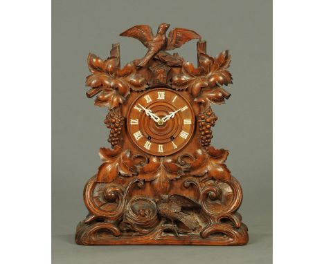 A 19th century cuckoo clock by J.B. Beha & Sons Eisenbach, the case carved with a cuckoo, fruiting vine and scrollwork and wi