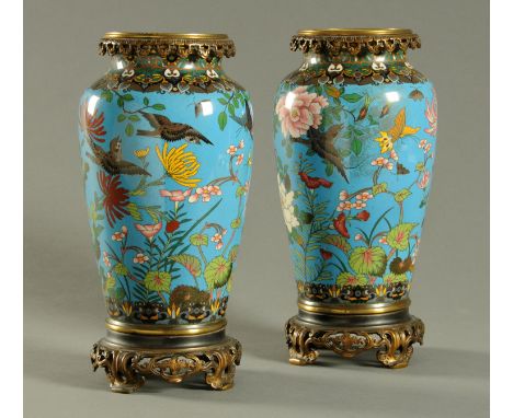 A pair of Japanese Cloisonne vases, decorated with birds and butterflies to blue ground and with integral metal bases.  Heigh