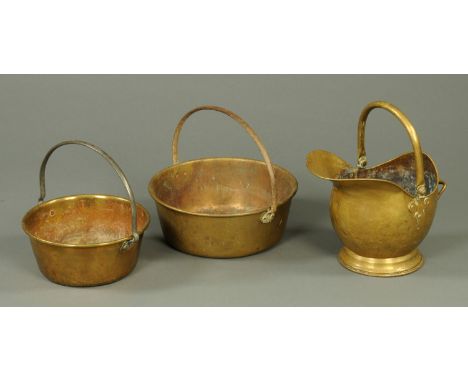 A Victorian helmet shaped brass coal scuttle, and two brass preserve pans. 