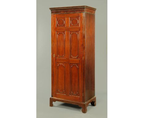 An early 19th century mahogany wardrobe, with moulded dentil cornice above a single door with panels and applied mouldings op