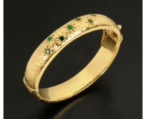 A 9 ct gold emerald set bangle, with safety chain, 21.8 grams gross (see illustration). 