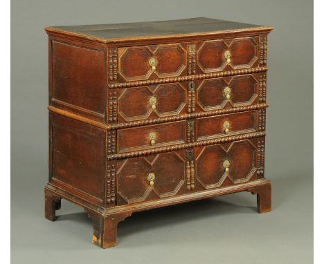 A Jacobean oak chest of drawers, two part, with cushioned drawer fronts, brass drop handles and raised on bracket feet.  Widt
