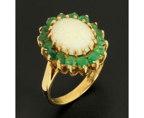 A 9 ct gold emerald and opal ring, size N.  CONDITION REPORT: This lot has a chipped emerald to one side which would in our o