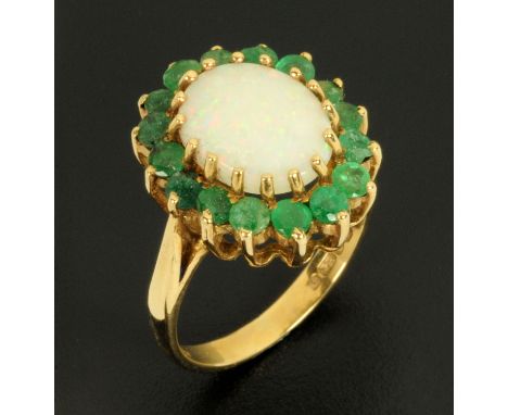 A 9 ct gold emerald and opal ring, size N.  CONDITION REPORT: This lot has a chipped emerald to one side which would in our o