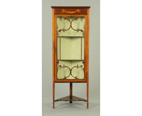 An Edwardian inlaid mahogany standing corner display cabinet, with moulded cornice above a ribbon and swag frieze, with glaze