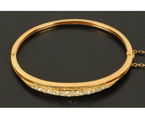 A diamond set bangle, 15 graduated diamonds to rose gold coloured bangle, with safety chain, gross weight 11.7 grams.  Intern