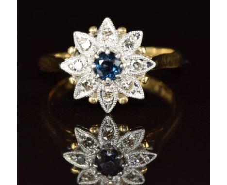 An 18ct gold ring set with a sapphire surrounded by diamonds in a floral platinum setting, 3.2g, size J