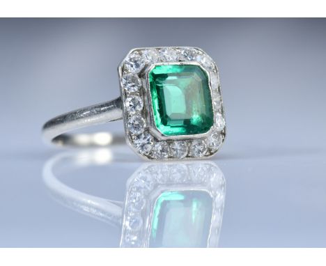 Art Deco platinum ring set with an emerald cut emerald of approximately 1ct surrounded by 16 round cut diamonds each approxim