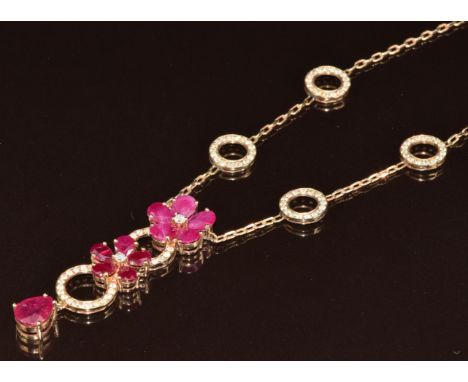 A 14k gold ruby and diamond necklace consisting of two circular flower cluster heads set with rubies, six large circular link