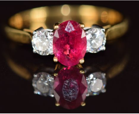 An 18k gold ring set with an oval cut ruby of approximately 1ct and two round cut diamonds, each approximately 0.28ct, 4.2g, 