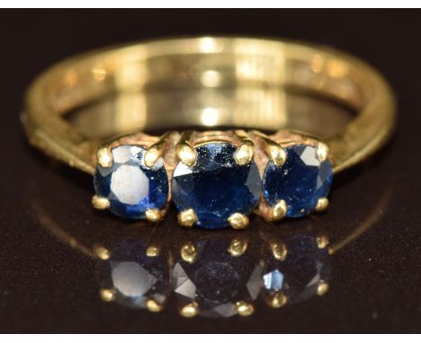 An 18ct gold ring set with three round cut sapphires, 3.3g, size N