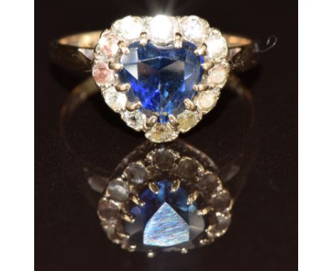 A 9ct gold ring set with a heart cut synthetic sapphire surrounded by paste stones, 2.5g, size L