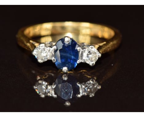 An 18ct gold ring set with an oval cut sapphire and two diamonds, 2.7g, size H
