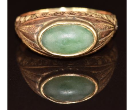 Victorian yellow metal ring set with a jadeite cabochon with engraved decoration to the shoulders, 8.1g, size Z