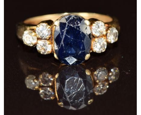 An 18ct gold ring set with an oval cut sapphire of approximately 1.8ct&nbsp;and three diamonds to each shoulder, 5.6g, size P
