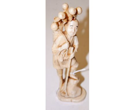 A Japanese Meiji period okimono, carved as a man in standing pose with garden tool in hand and basket of flowers upon his bac