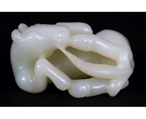 A CHINESE PALE CELADON JADE MODEL OF A HORSE, lying on its side, 2.25in(5.8cm) wide.