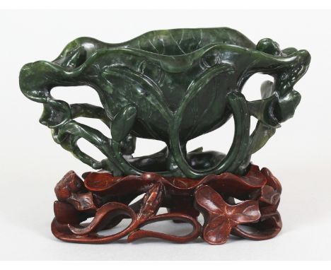 AN EARLY/MID 20TH CENTURY CHINESE SPINACH JADE MODEL OF AN OPEN LOTUS, together with a pierced and fitted hardwood stand, the