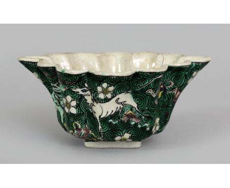 AN UNUSUAL LATE 17TH CENTURY CHINESE KANGXI PERIOD FAMILLE VERTE BISCUIT PORCELAIN LIBATION BOWL, the lobed sides enamelled w