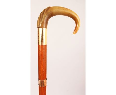 A RHINOCEROS HORN HANDLED WOOD WALKING STICK, with good quality gold-metal mounts inscribed and dated 1910, the carved rhino 
