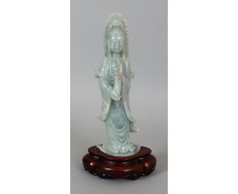 A CHINESE CELADON GREEN JADE FIGURE OF GUANYIN, together with a fitted wood stand, 13.5in(34.3cm) high overall, the figure it