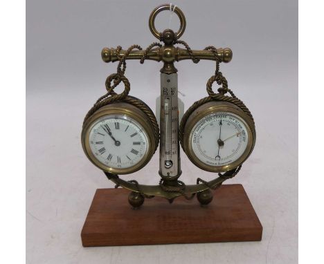 A nautical brass desk clock barometer as an anchor with centre thermometer divider raised on an unpolished mahogany plinth, g