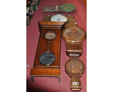 An oak aneroid wheel barometer; together with a 19th century mahogany clock barometer case, an oak clock barometer case and a