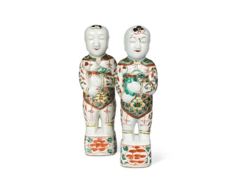 A Pair of Chinese famille verte porcelain standing smiling boys, Qing Dynasty, Kangxi (1662-1722),each holding a vase with lo