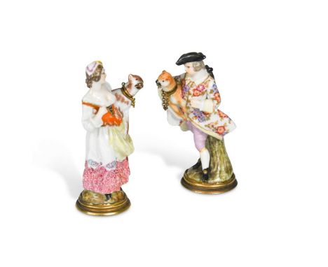 A pair of Meissen gilt metal mounted scent bottles,modelled as a lady and gentleman in 18th century attire, each holding a do