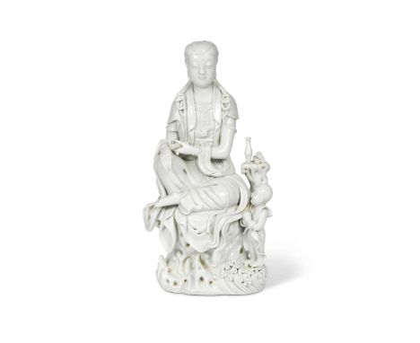 A Chinese Blanc de Chine (Dehua) figure of Guanyin, late 19th/early 20th century,seated on a rocky dais wearing flowing robes