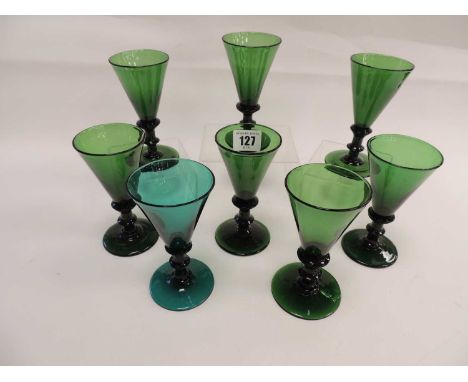 SEVEN ANTIQUE GREEN GLASS WINE GLASSES, with knopped stems and turned circular bases, together with another similarProvenance