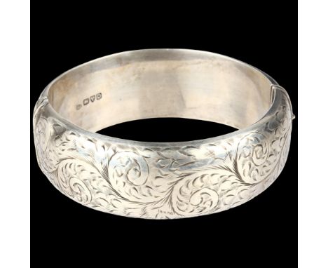 A mid-20th century silver hinged bangle, maker S&E, Chester 1954, allover engraved foliate decoration, band width 22.7mm, int