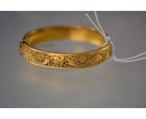 A late Victorian gold (unmarked) hinged bangle, one half pierced with a grape and vine leaf pattern, presentation inscription