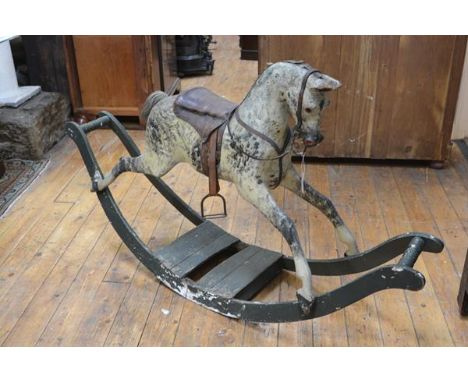 An English painted wooden rocking horse, c. 1900, possibly G & J Lines or Ayres, with glass eyes, dappled body, leather saddl