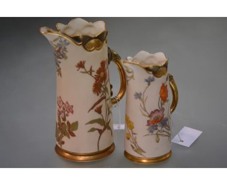 Two 19th century Royal Worcester ewers, each of tapering cylindrical form, painted with floral sprays against a blush ivory g