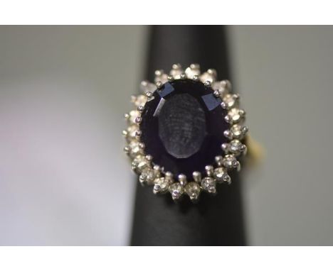 An amethyst and diamond ring, the large oval step-cut amethyst claw-set within a band of twenty-two single-cut diamonds, on a