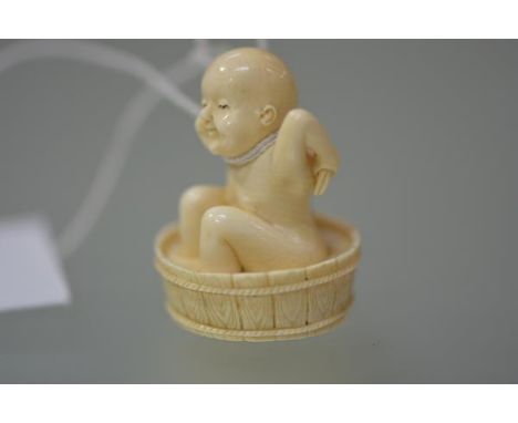 A Japanese ivory netsuke, carved as a child washing in a tub, seal mark to base. 40mm