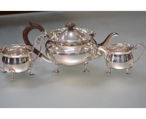A George V silver three piece tea service, Sheffield 1930, each piece of bellied form, with scalloped rim and raised on splay