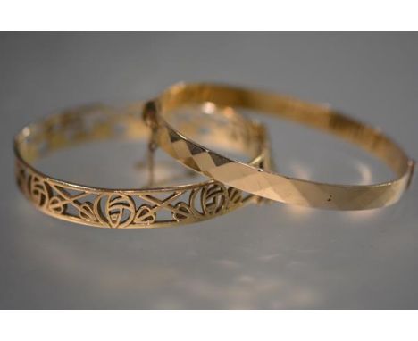 A 9ct yelllow gold bangle, in the Art Nouveau taste, pierced with stylised foliated motifs; together with a gold-plated bangl