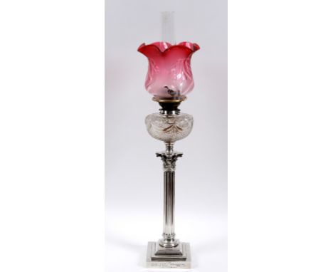 A late Victorian plated Corinthian column table oil lamp, with a cranberry glass shade and a cut glass reservoir, on a steppe