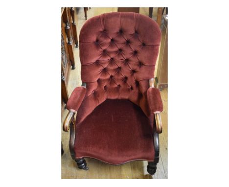 A Victorian button back armchair, on turned front legs