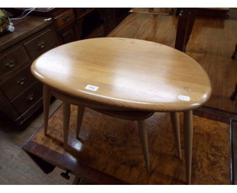 A nest of three Ercol elm pebble tables, the largest 65 cm wide, and an Ercol footstool (no cushion) (2) Condition report Rep