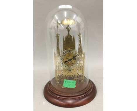 A brass skeleton clock under a glass dome