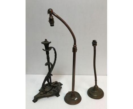 Two early 20th Century adjustable brass table lamps raised on circular bases together with a Victorian wrought iron lamp with