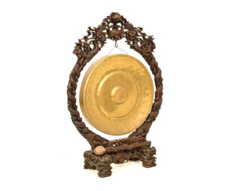 Late 19th/early 20th Century Chinese brass and carved hardwood floor-standing gong, the hammered dished gong with raised conc