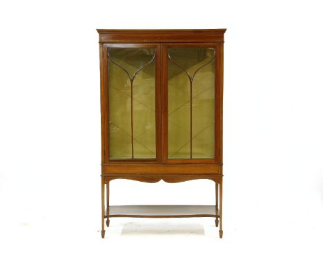 An Edwardian inlaid mahogany glazed display cabinet, the moulded cornice over two glazed doors over a suspended shelf on spad