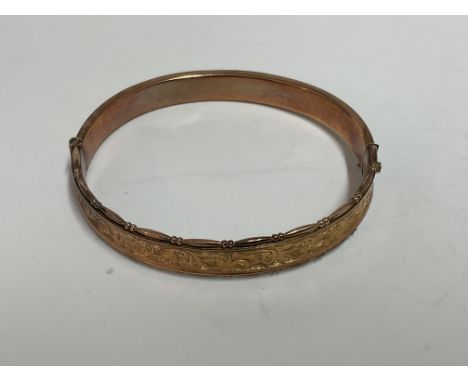 A 9ct gold bangle with engraved decoration,  approximately 10.8g.