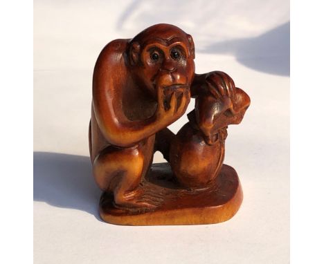 JAPANESE NETSUKE OF A CROUCHING MONKEY WITH A BAG